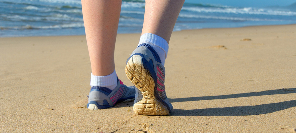 person wearing flexible barefoot shoes while walking on the beach